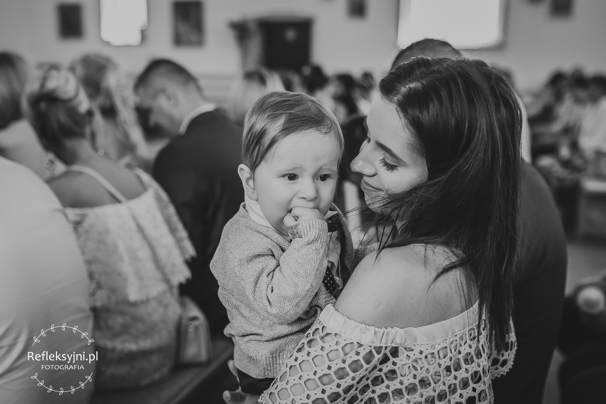 Mama trzyma dziecko na Chrzcie