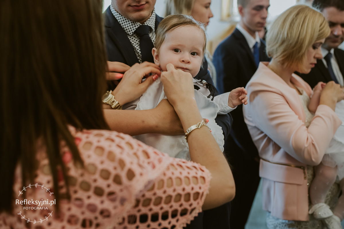 Tata trzyma dziecko na Chrzcie