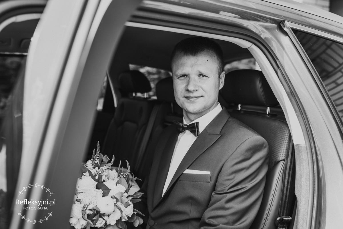 Pan Młody siedzący w samochodzie ślubnym