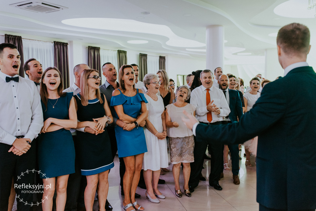 Zdjęcie przestawia gości na weselu bawiących się podczas oczepin ślubnych