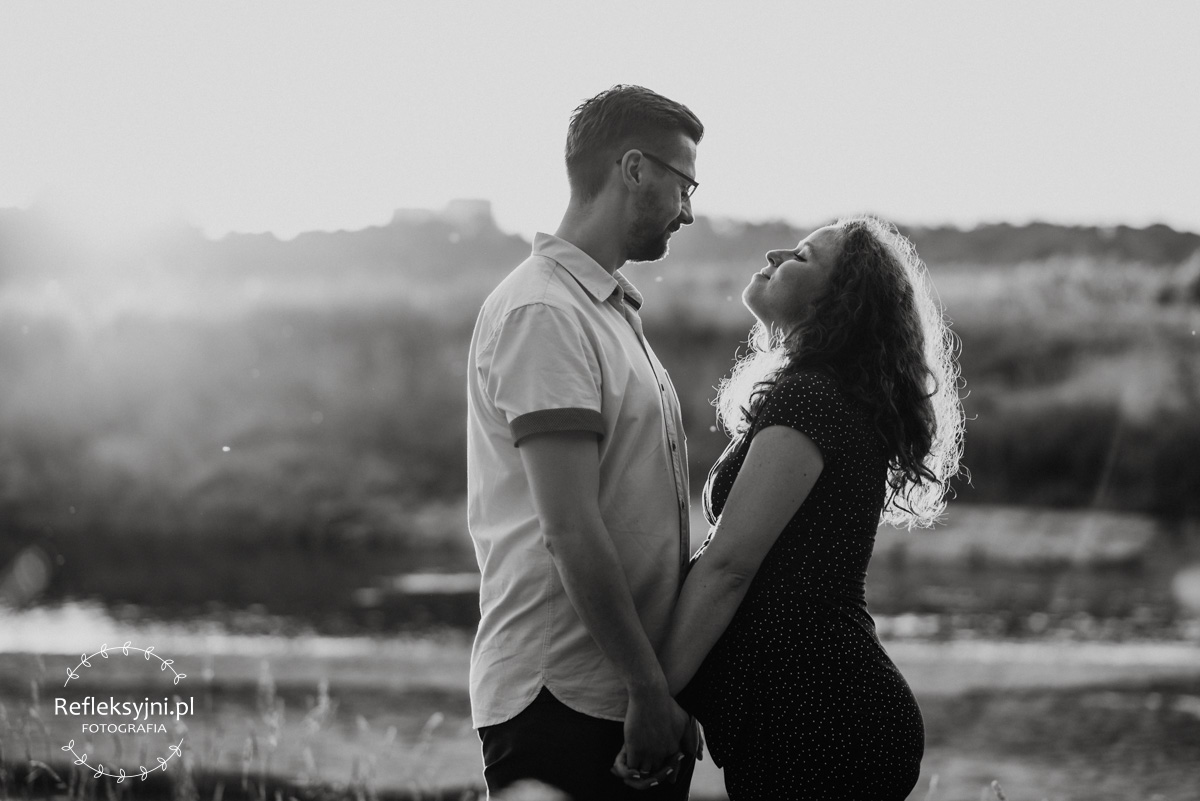 Ruda kobieta w ciąży i mężczyzna stojący na plaży nad Wisłą